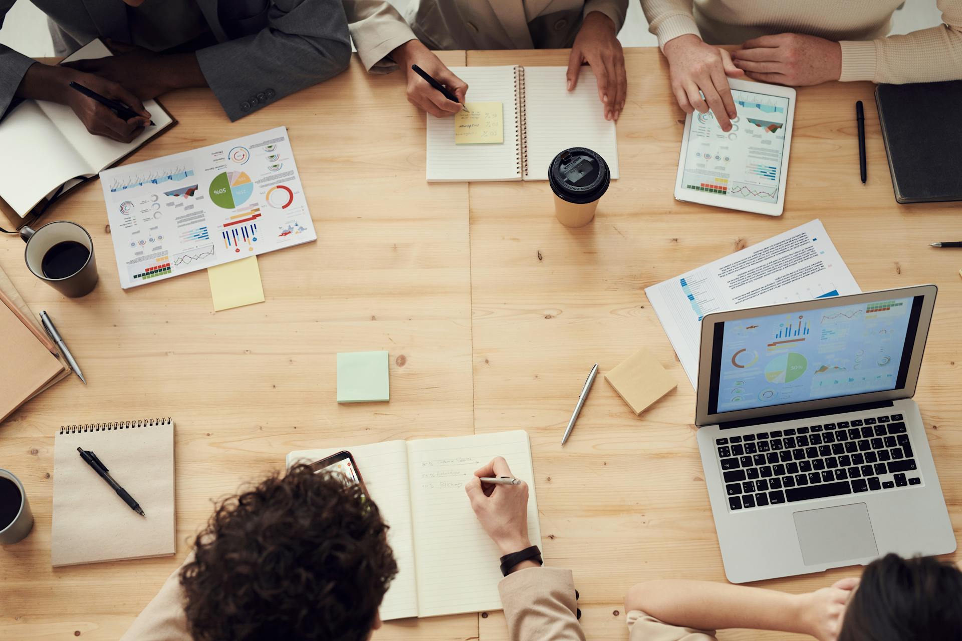 a table with a computer, data spreadshets and sticky notes