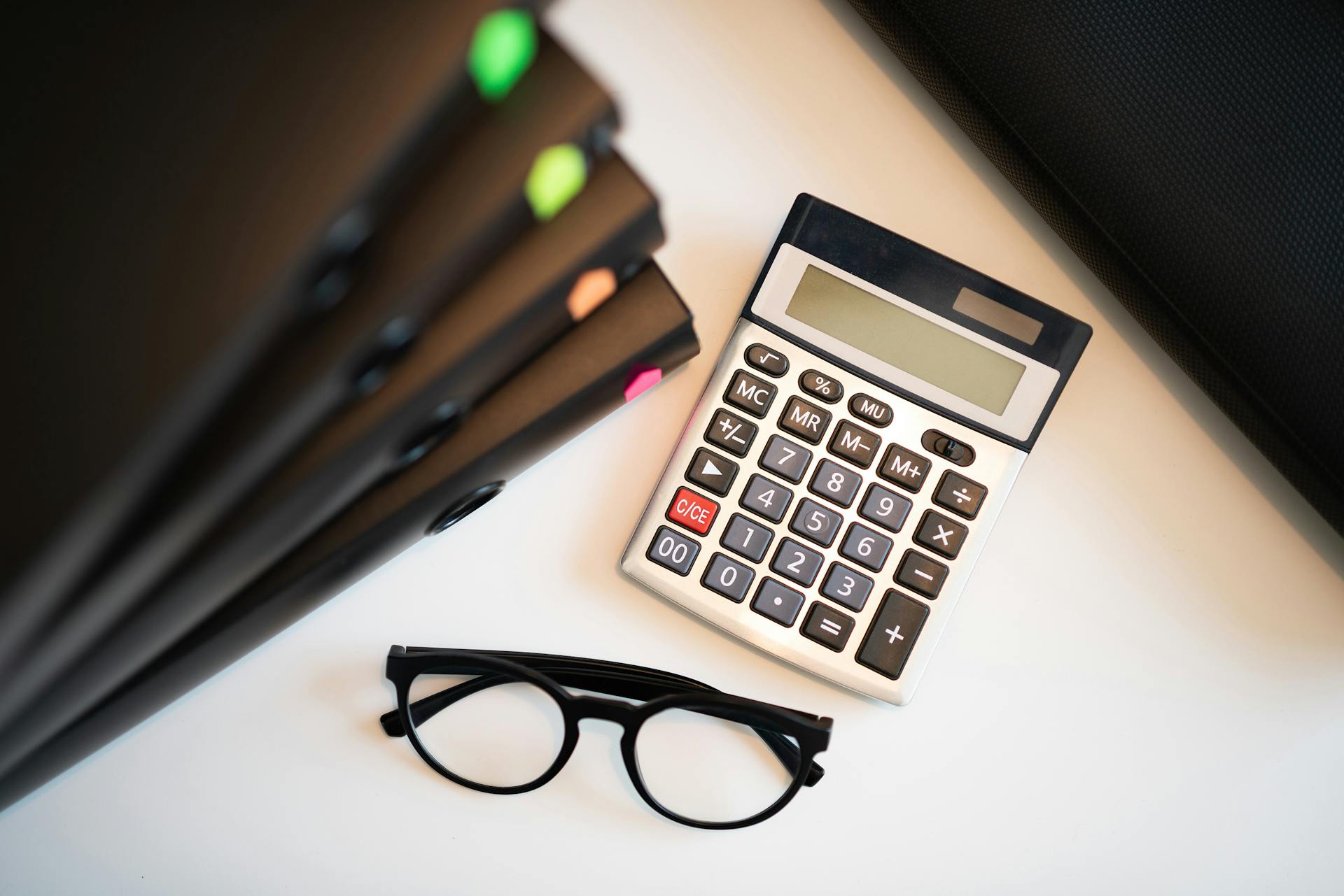 a calculator on a text next to a pile of files
